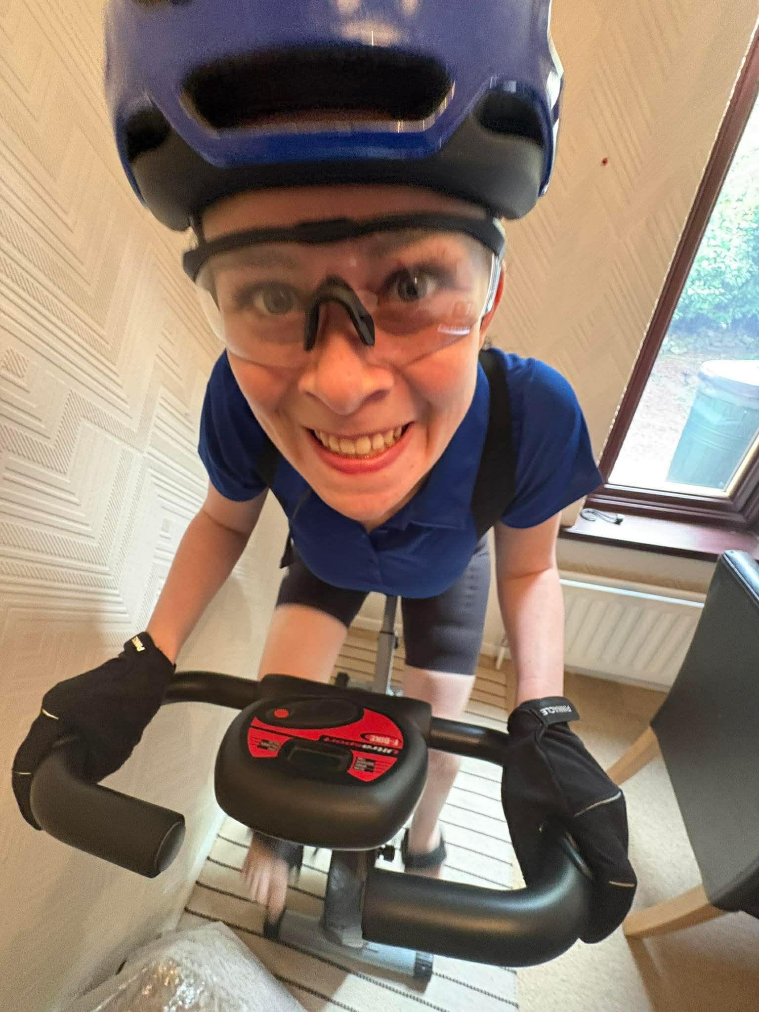 Izzy on an exercise bike wearing a blue helmet and glasses